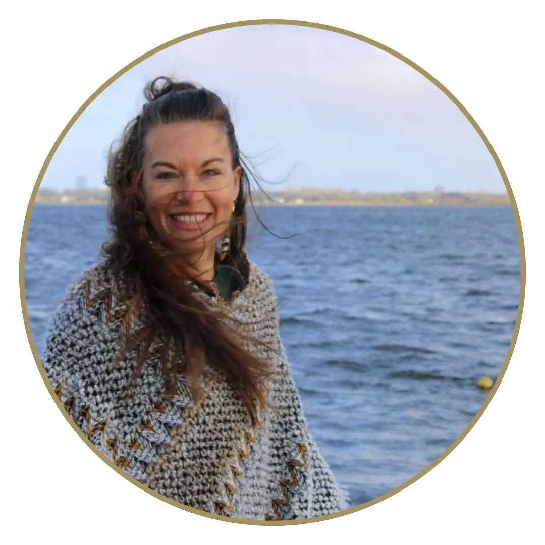 Angie van Hunnik staat voor het Gooimeer, haar lange bruine haar wappert in de wind. Ze lacht en heeft een grijze trui aan.