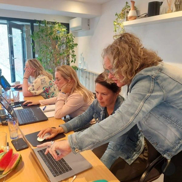 Workshop digitale toegankelijkheid: ondernemers werken samen aan laptops terwijl een expert meekijkt en aanwijzingen geeft voor een gebruiksvriendelijke website