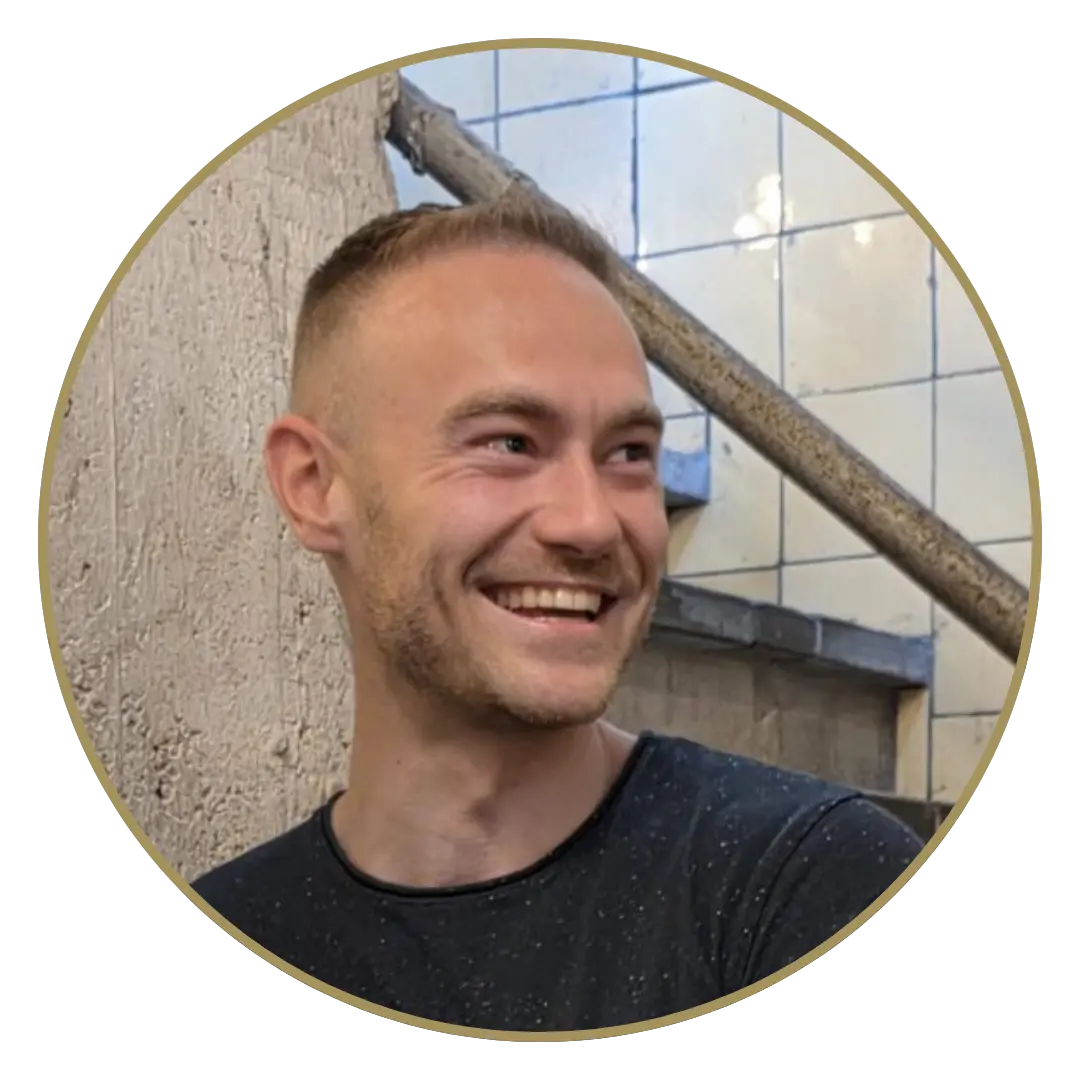 Foto van Justin van den Berg, hij kijk lachend naar links.. Hij heeft gemillimeterd haar en draagt een zwart tshirt.