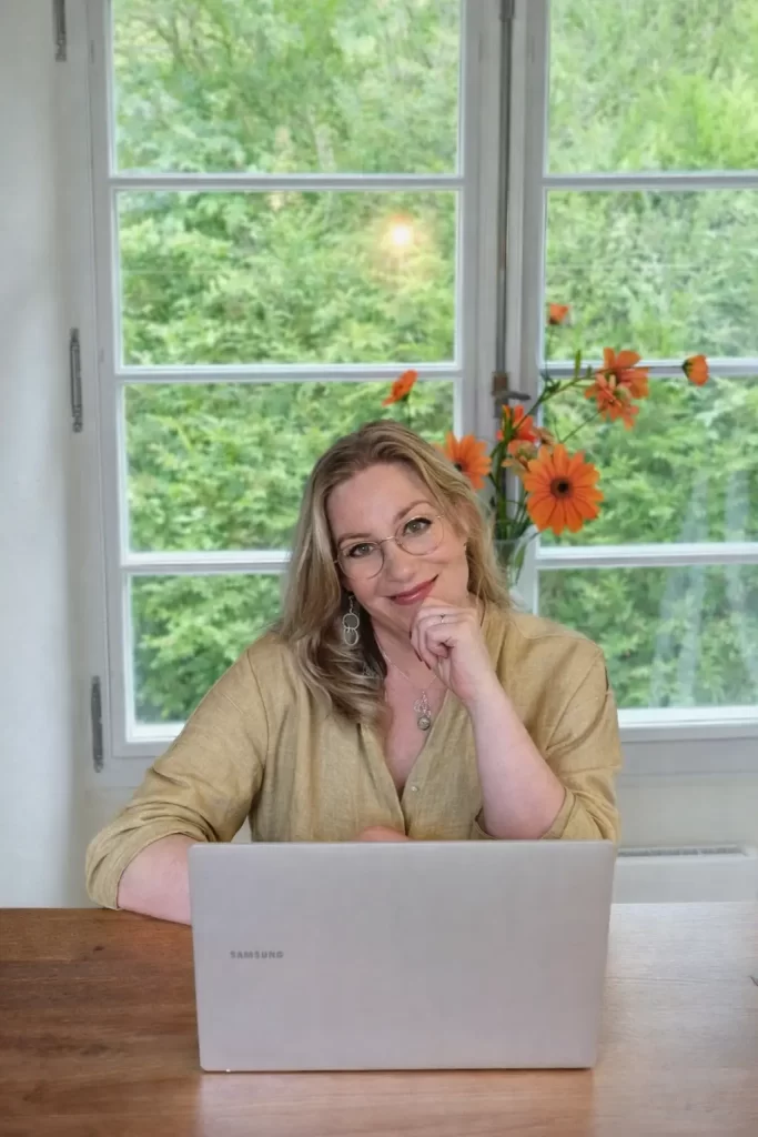 Marion Terpstra zit aan haar bureau met laptop, voor het raam met groen uitzicht, werkend aan een maatwerk website voor Studio The WebCreator