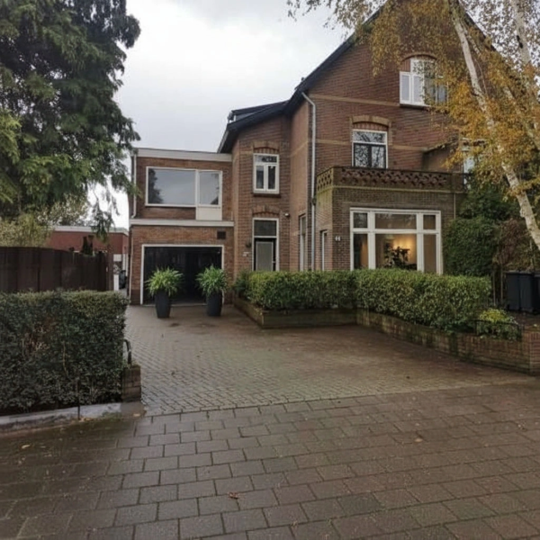 Een vrijstaande woning met een oprit en een tuin ervoor.