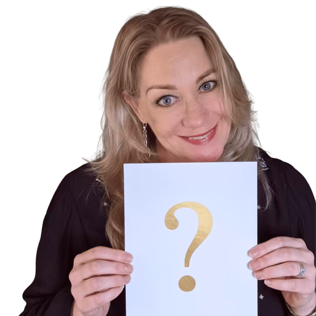 Marion kijkt schuin de camera in, ze lacht. ze houdt een wit a4 papier voor zich met daarop een gouden vraagteken.