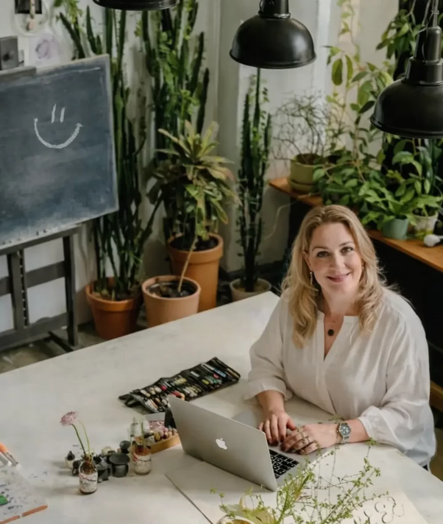 Marion Terpstra werkt aan branding en strategie aan een grote werktafel met laptop, moodboards en creatieve materialen in haar studioomgeving